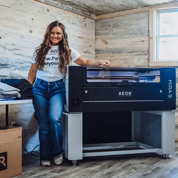 photo of Cassidy standing in her studio next to her Mira 9, smiling.