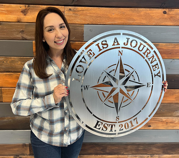 Emily Caroline holding a metal sign shapped like a compass, and says love is a journey