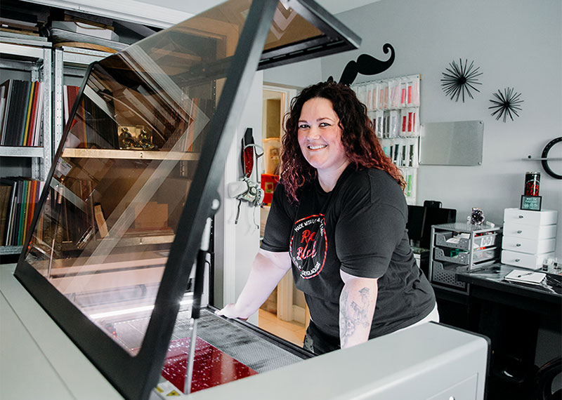 photo of Crystal standing over her Aeon laser, smiling