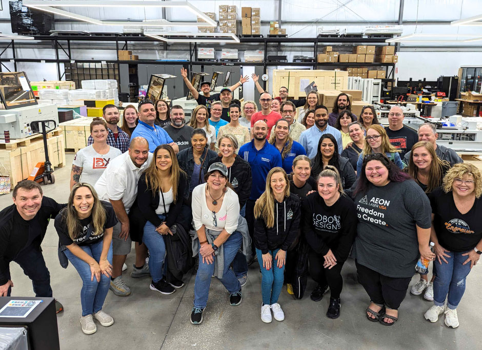 large group of people huddled together and smiling in the Aeon Laser USA warehouse