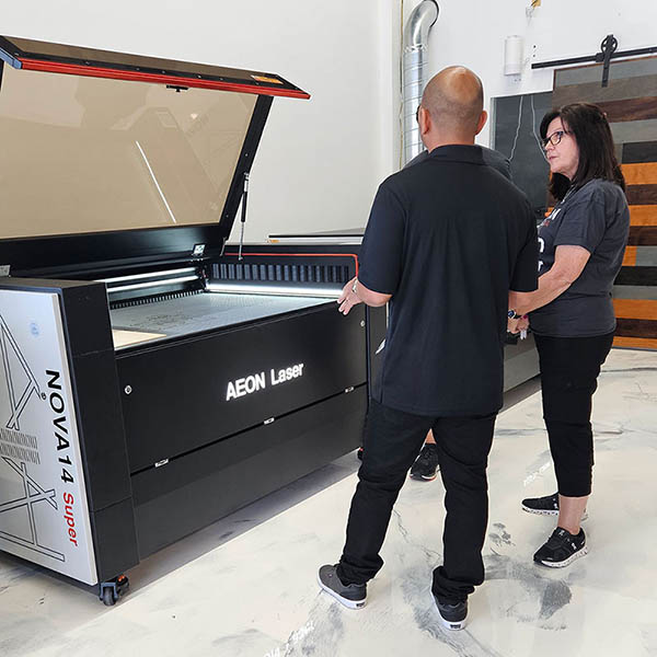 Product specialist and person looking at an Aeon laser together in the Aeon Laser USA showroom