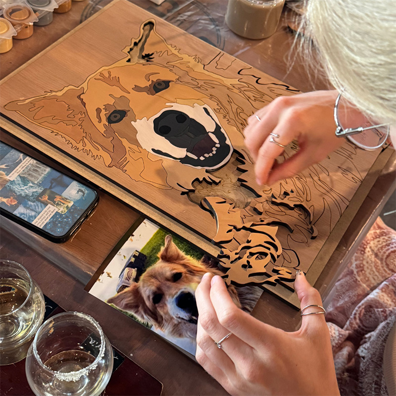 photo of a person putting together custom cut wooden pieces to create a portrait of a dog