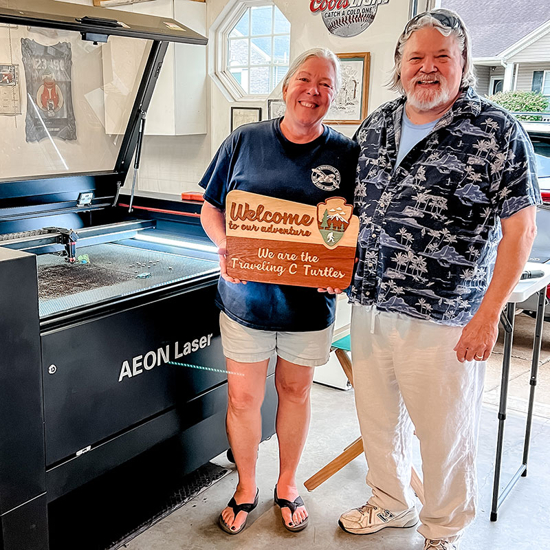 photo of Connie and Jeff, standing by their laser, smiling and holding a sign